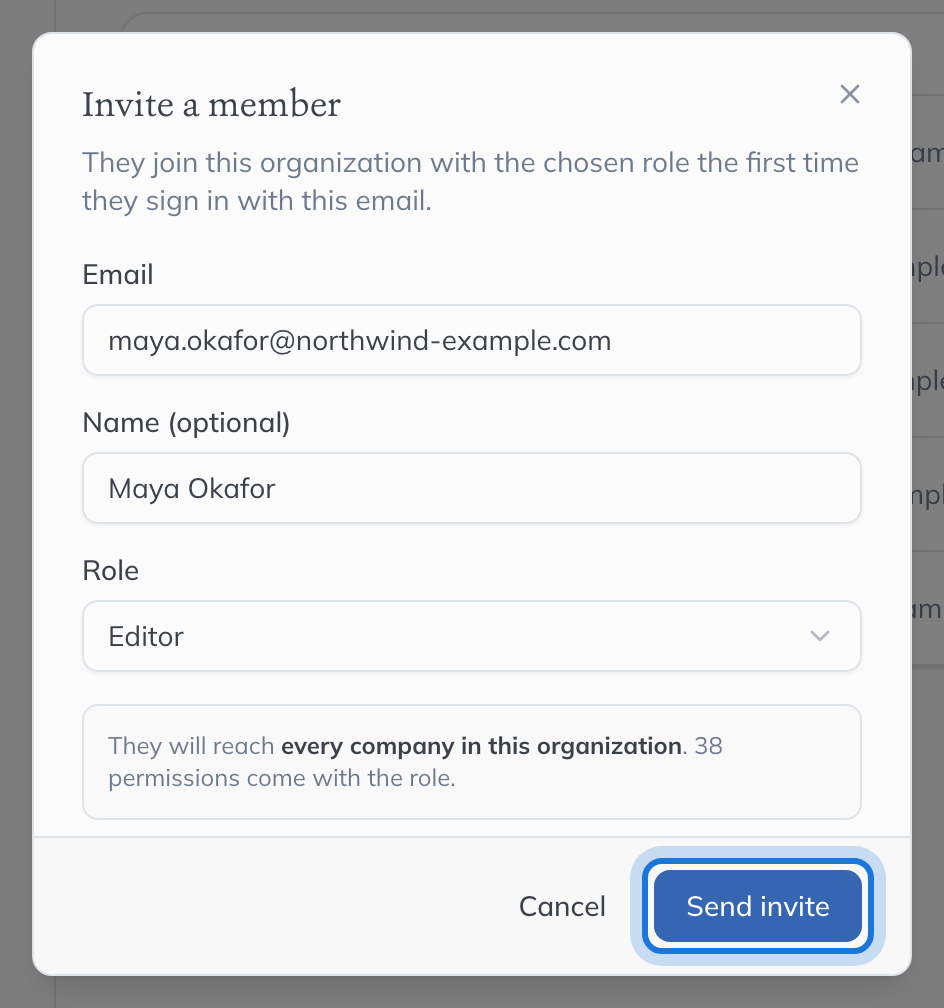 The Invite a member dialog, filled in for Maya Okafor with a role chosen and the reach of that role spelt out beneath it.